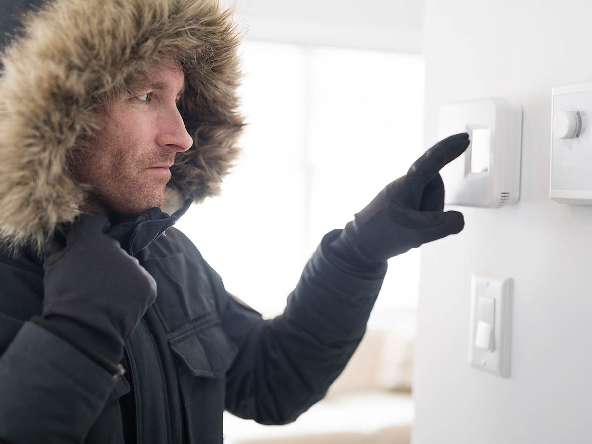 Sanitär Express – Mann mit einer Jacke und Handschuhen schaut auf einen defekten Thermostat+