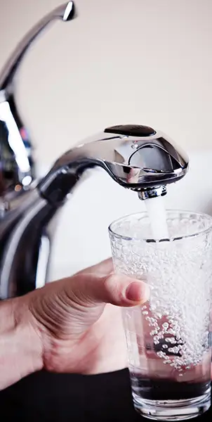 Sauberes Wasser fließt aus dem Wasserhahn ins Glas